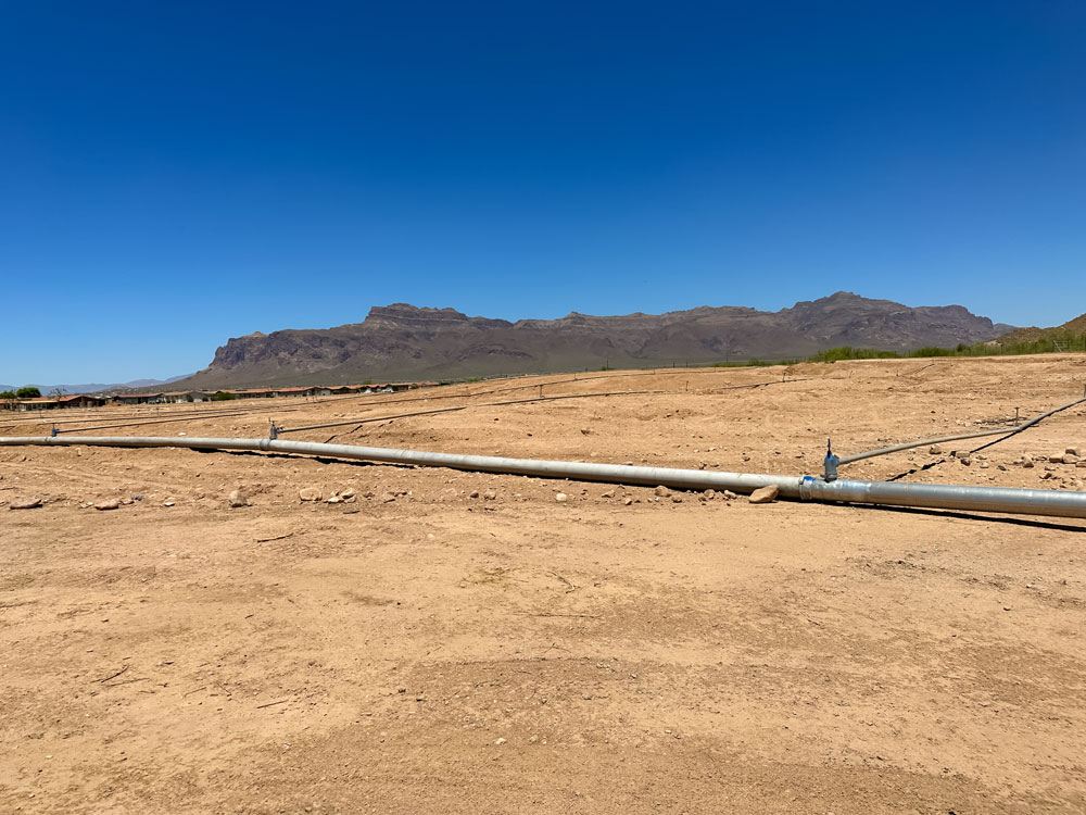 A pipe in the desert with mountains in the background.