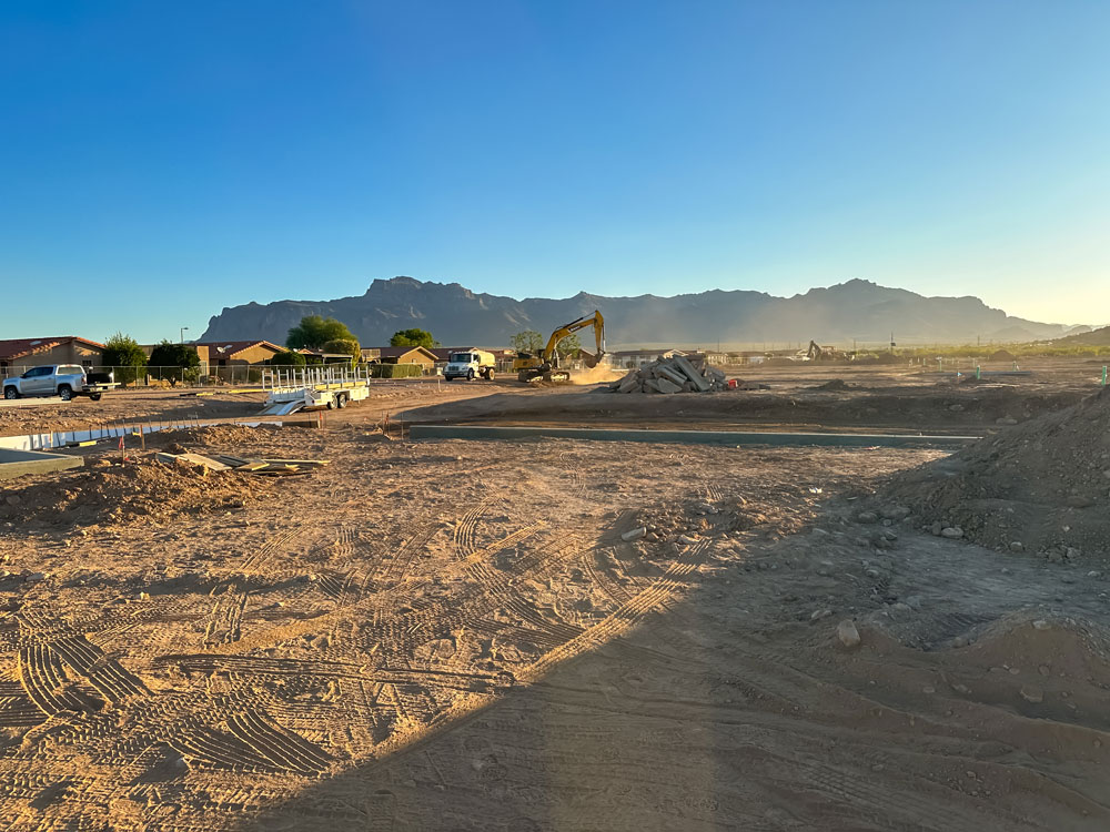 A construction site in the desert with mountains in the background.