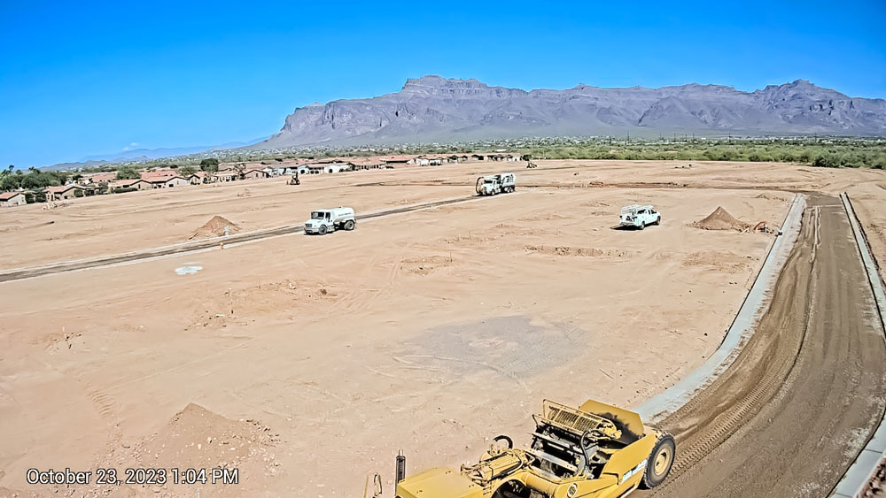 An aerial view of a construction site with mountains in the background.