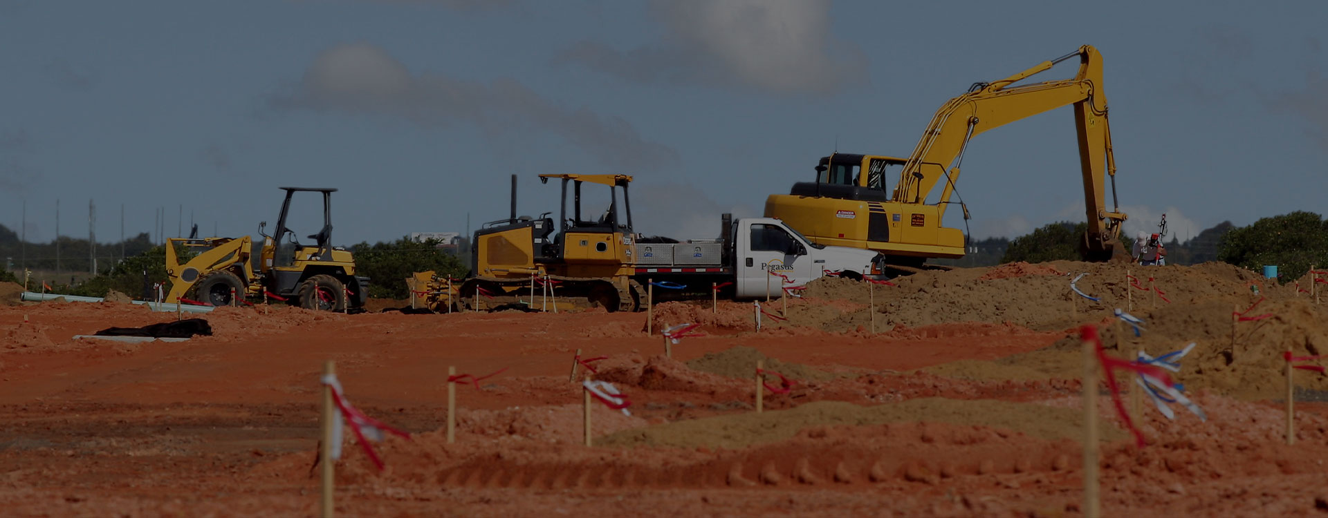 A group of construction equipment on a dirt field.