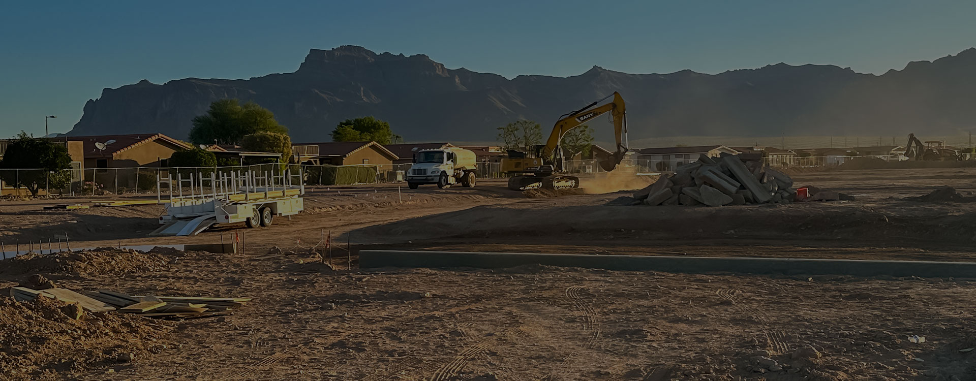 A construction site in the desert with mountains in the background.