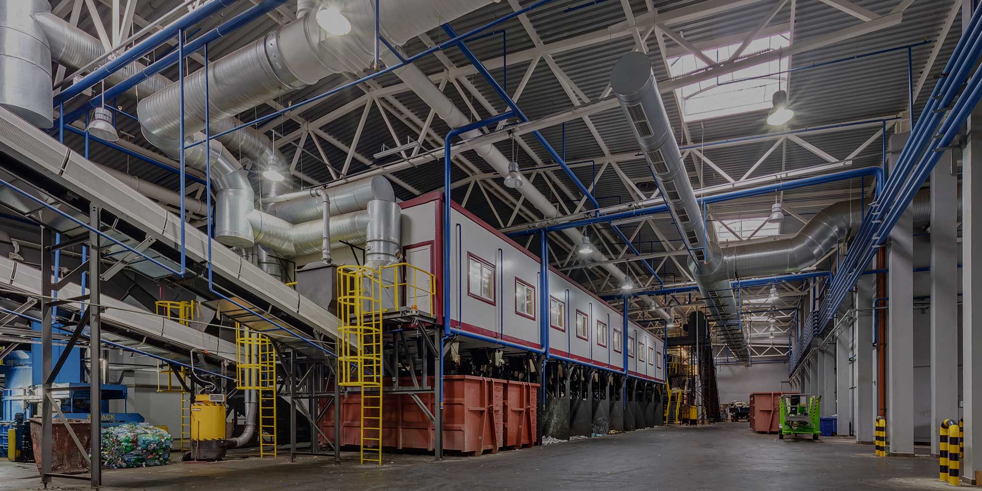 The inside of a factory with blue and yellow pipes.