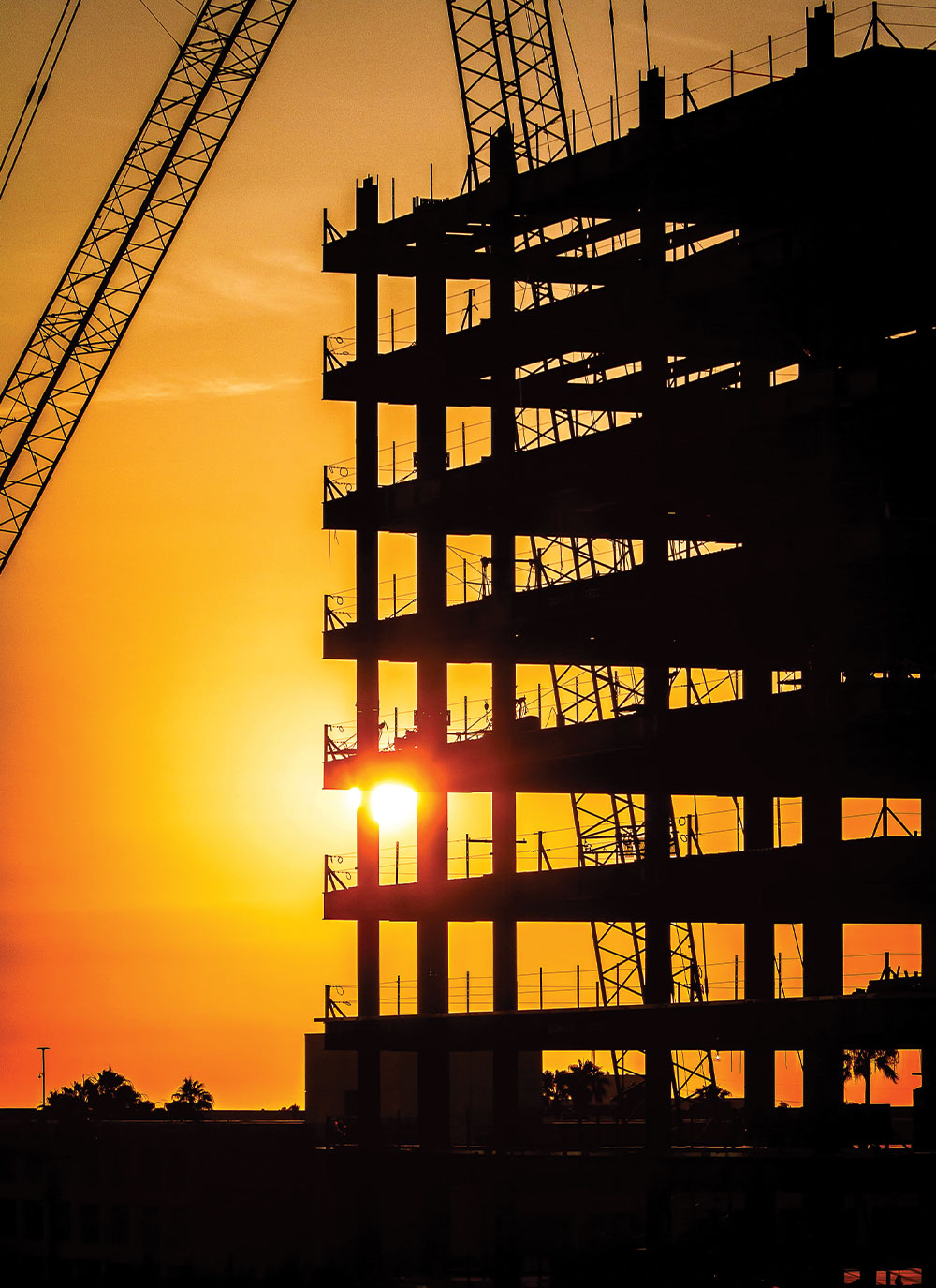 A silhouette of a building under construction at sunset.