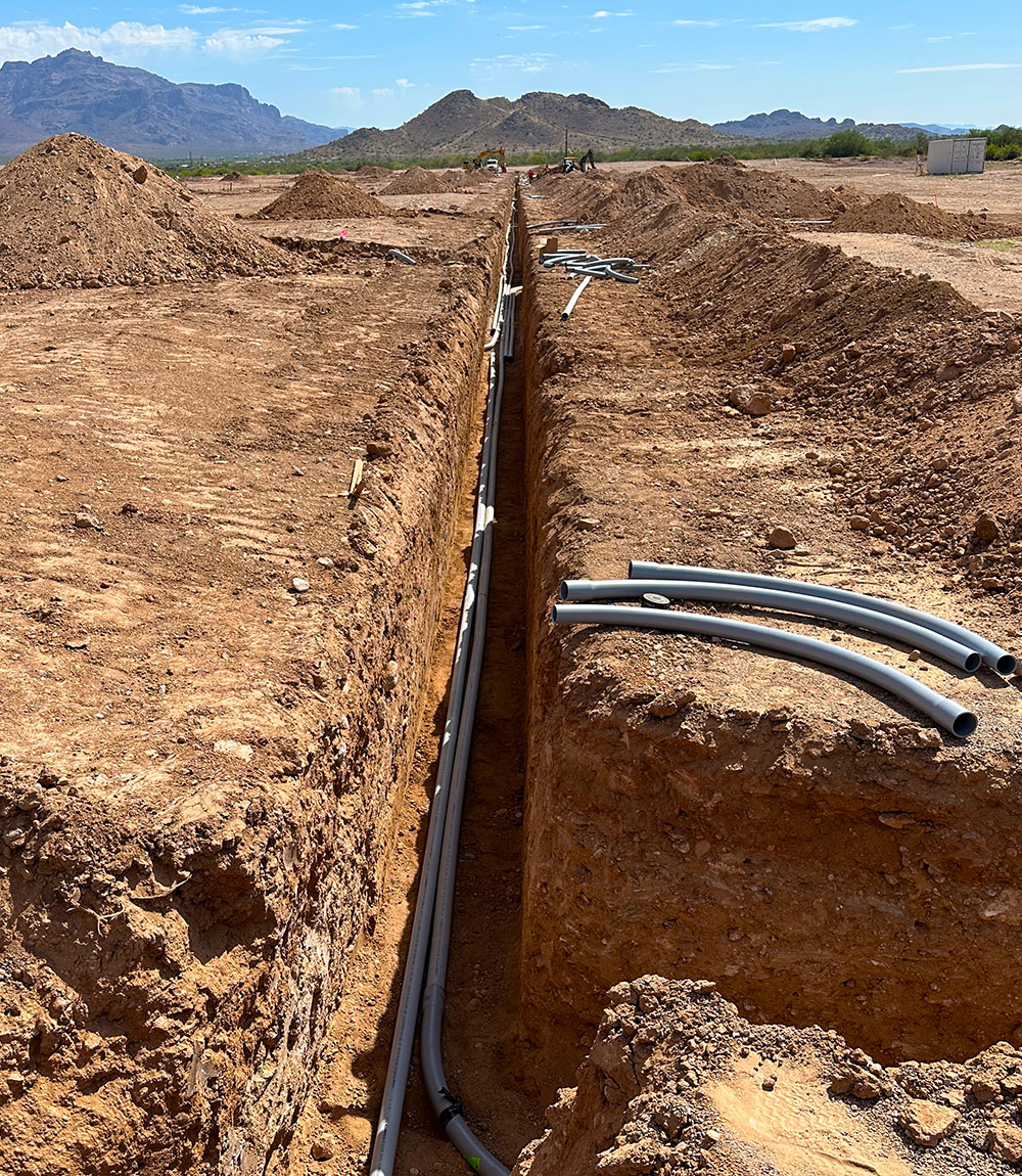 A trench in the ground with pipes and hoses.