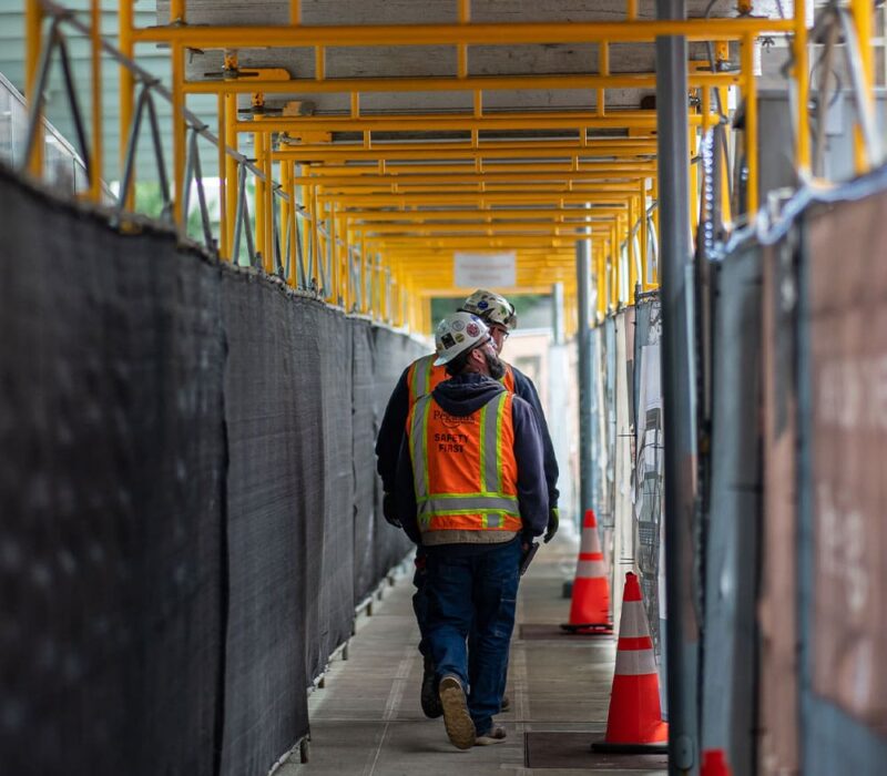 Two construction workers walking down a hallway.