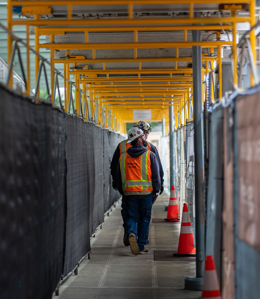 Two construction workers walking down a hallway.