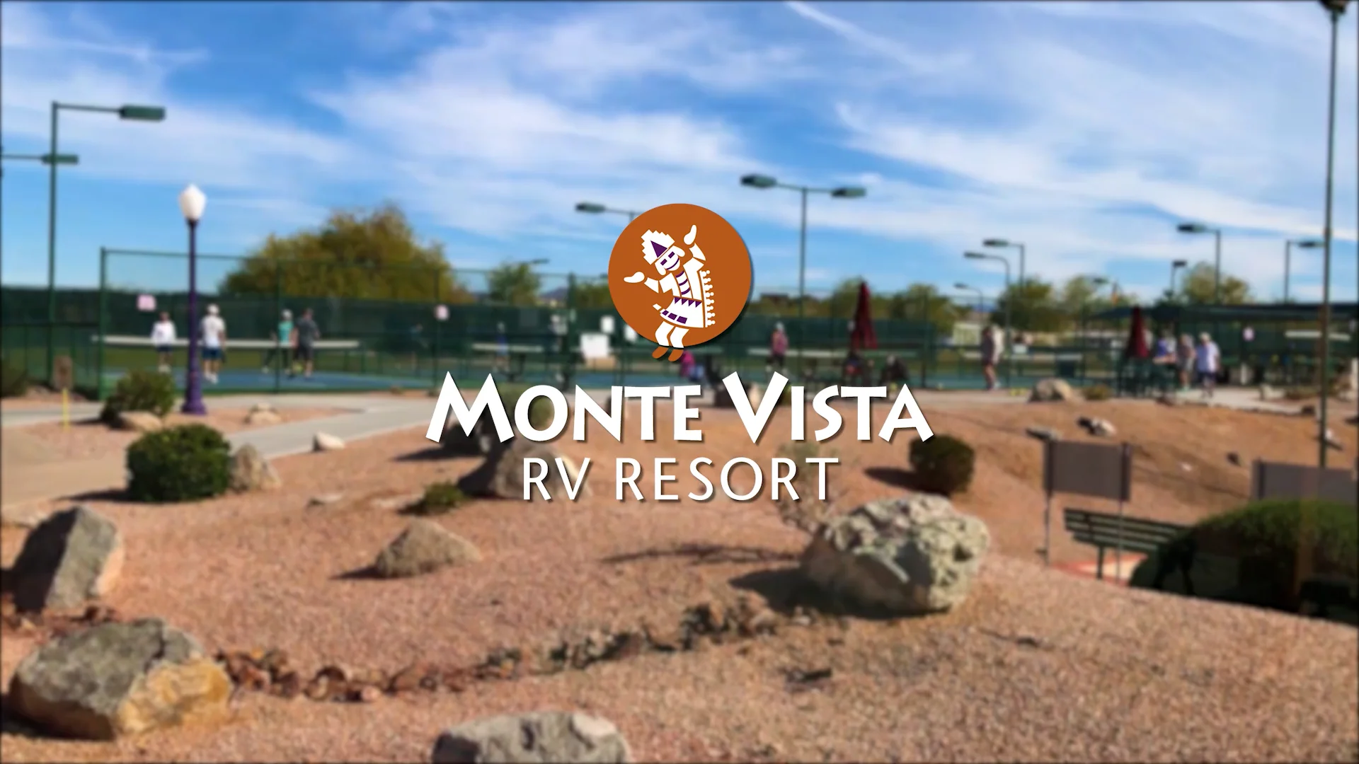 A landscaped outdoor area with desert plants and rocks is shown, along with a tennis court in the background. The overlay text reads Monte Vista RV Resort with a logo featuring a lizard.